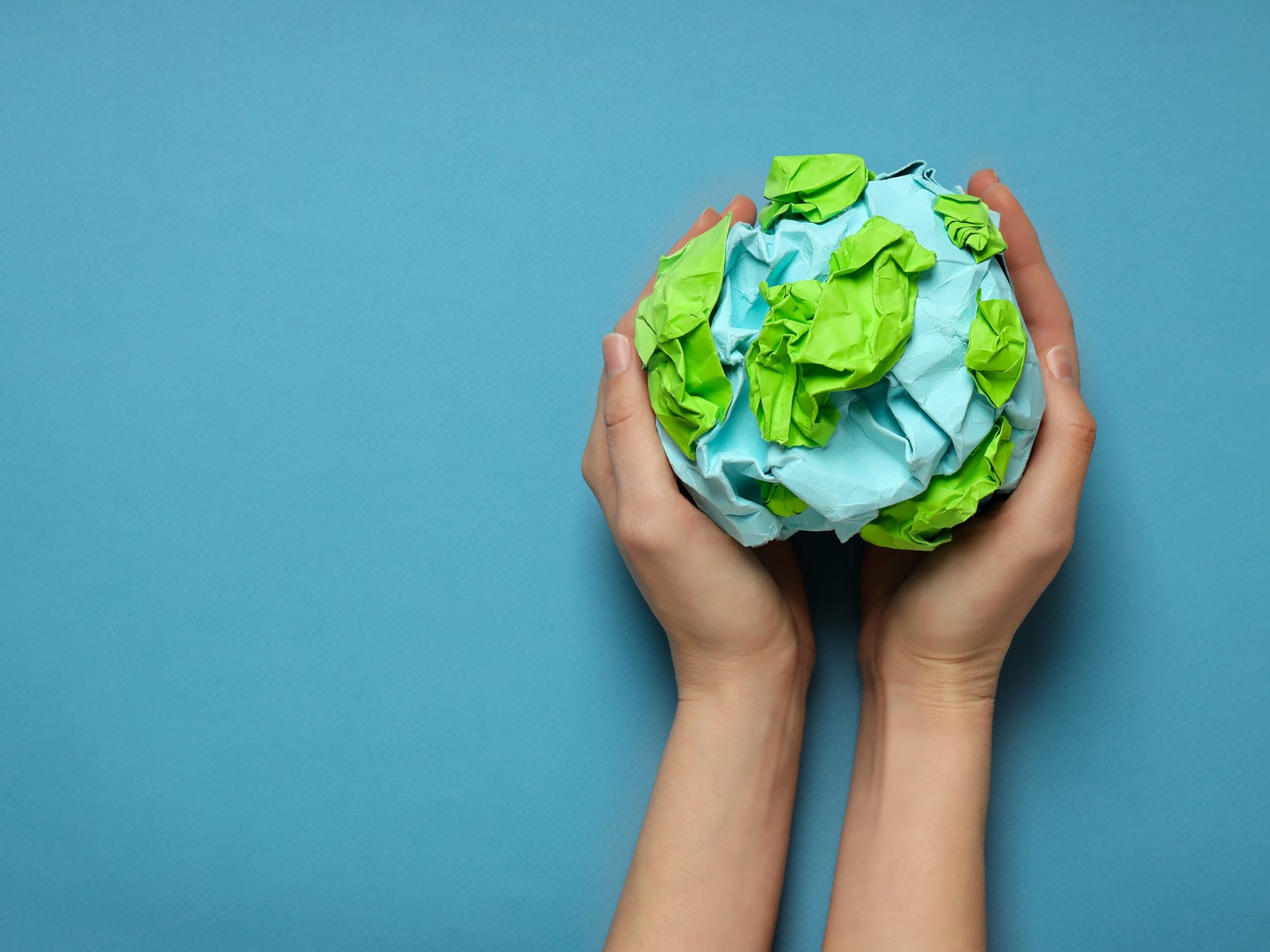 Hands holding a globe made out of paper