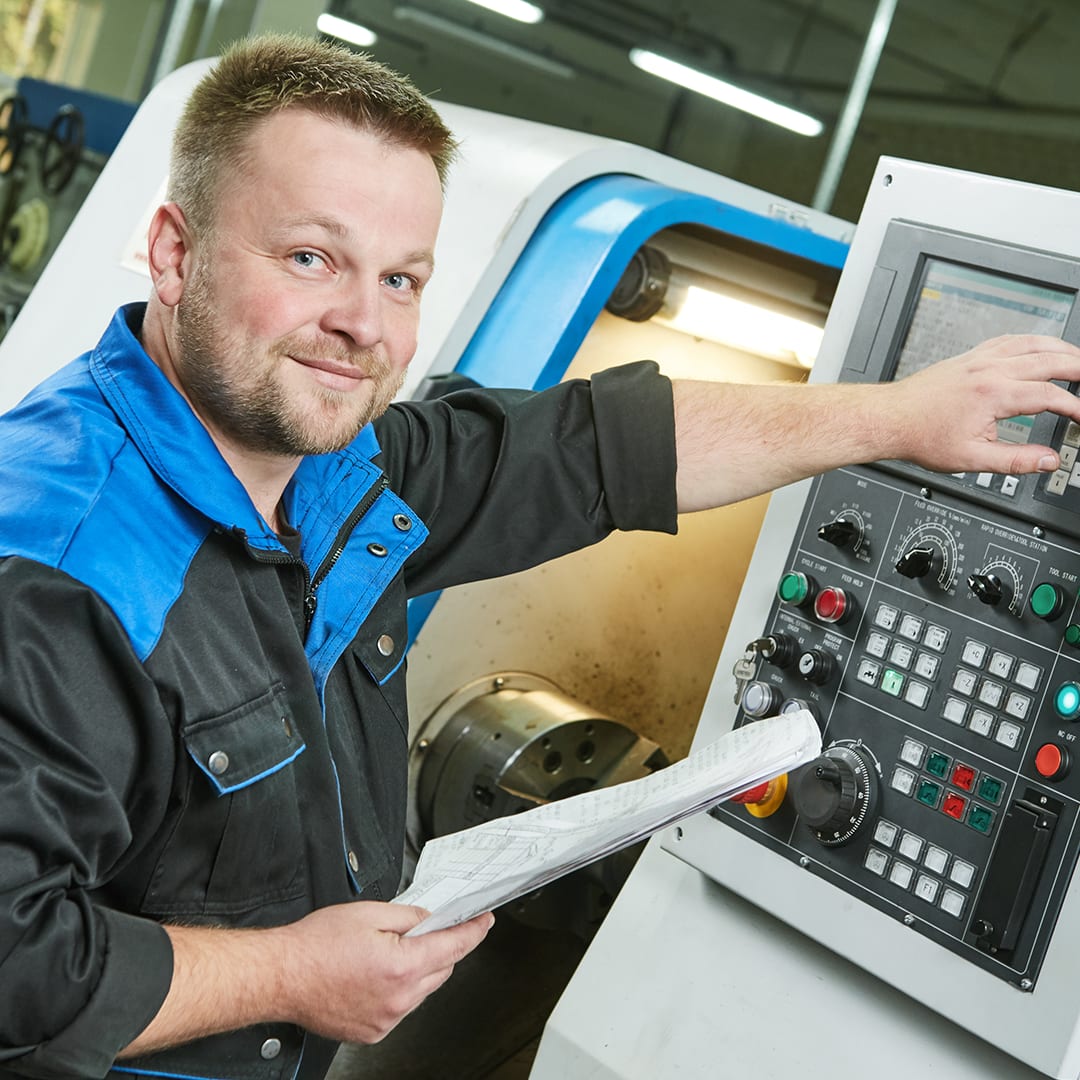 Mann bedient CNC-Drehmaschine in der Metallbearbeitung