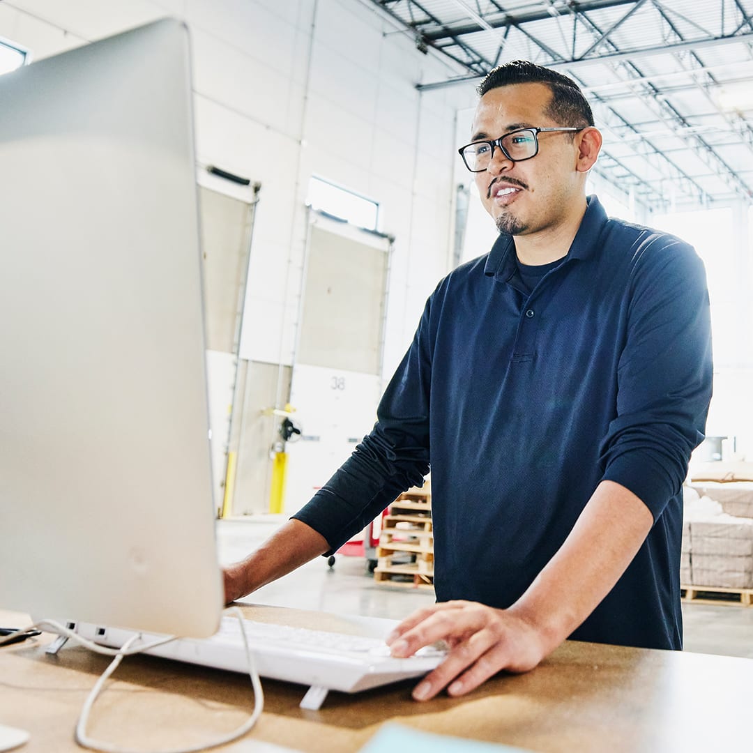 Mann am PC in industrieller Halle