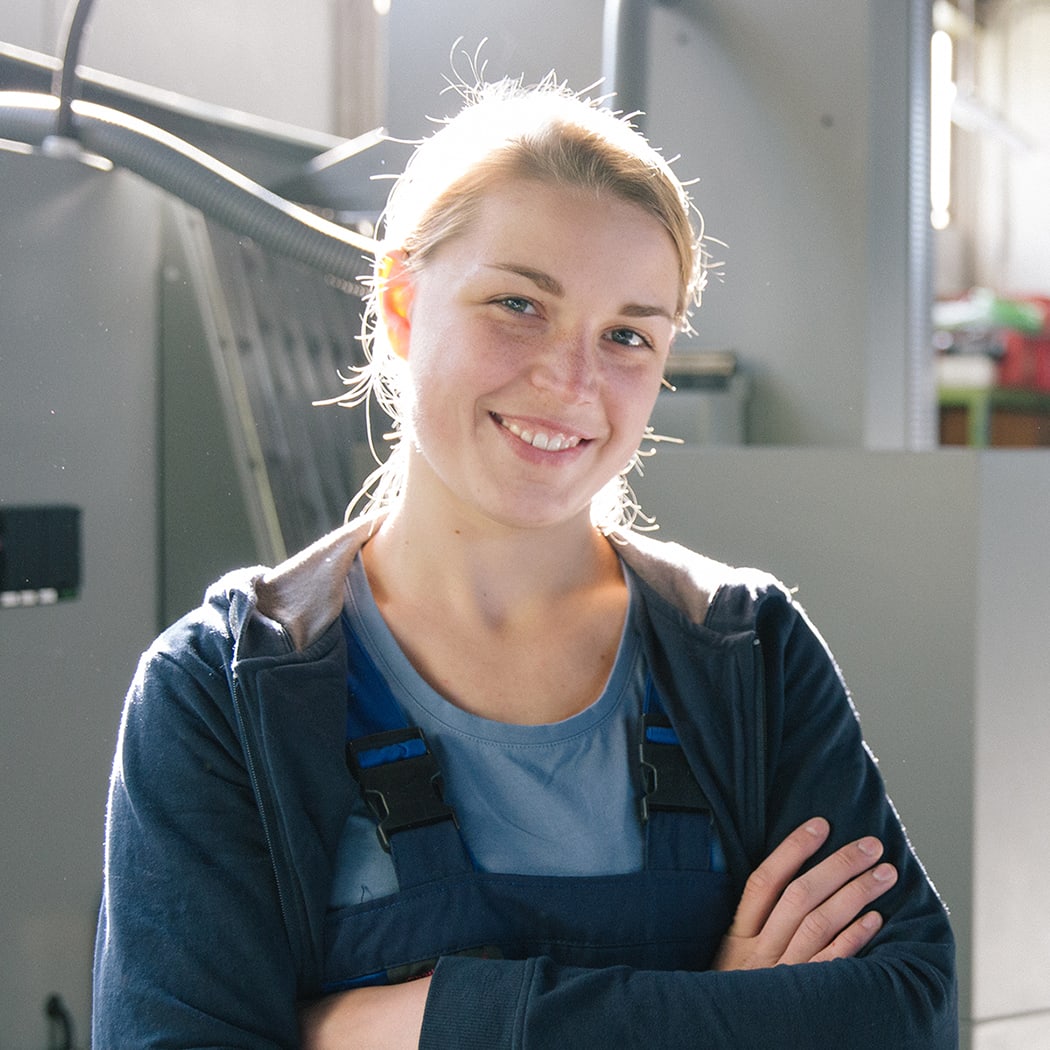 Frau in Fabrik vor Maschine