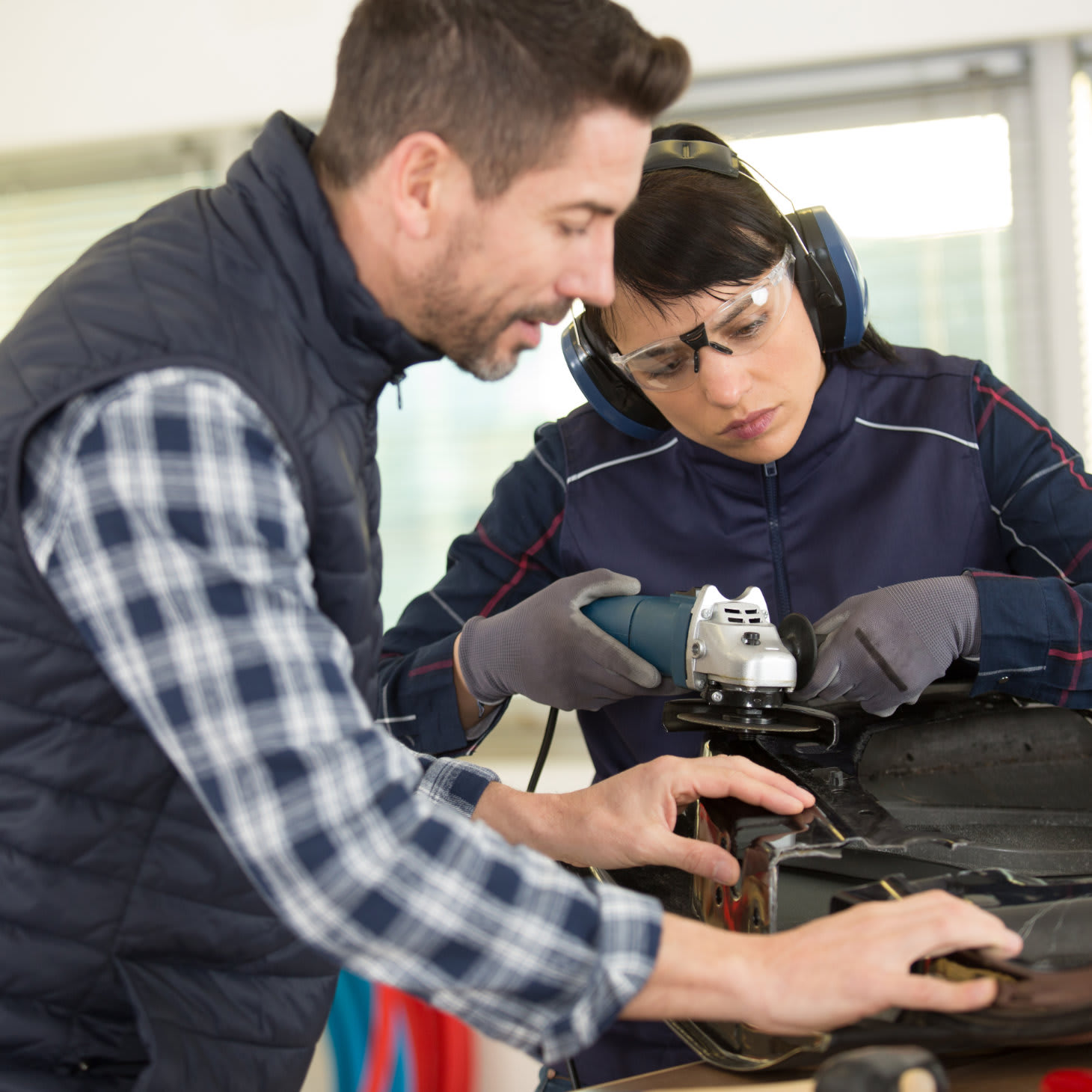 Ein Mann und eine Frau schleifen zusammen ein Metallstück