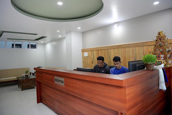 Teak wood reception desk counter with receptionist workstation and decorative shrine.