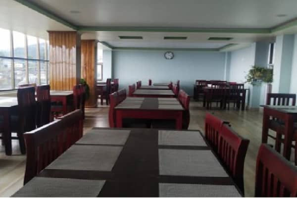 Restaurant dining hall perspective showing timber dining chairs and placemats.
