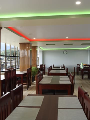 Restaurant interior featuring timber clad pillars and ambient cove ceiling lighting.