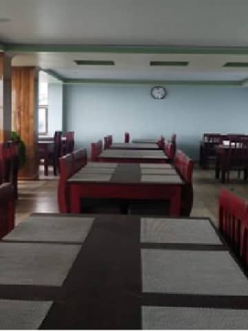 Restaurant dining hall perspective showing timber dining chairs and placemats.