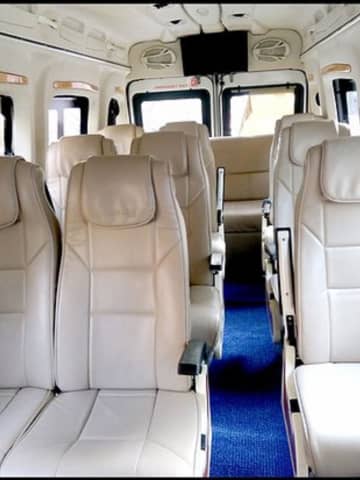 Force Tempo Traveller luxury cabin featuring individual beige leather pushback reclining seats, armrests, and central carpeted aisle.