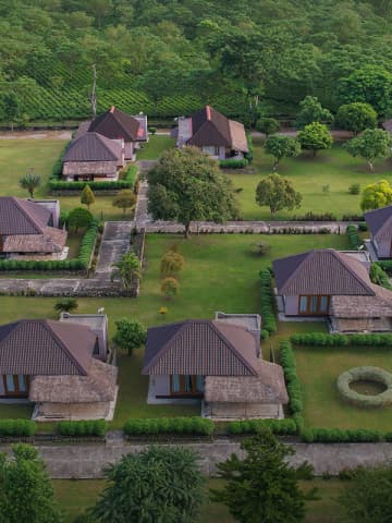 Panoramic drone capture of Musa Jungle Retreat standalone cottages, lawn gardens, and surrounding tea estate.
