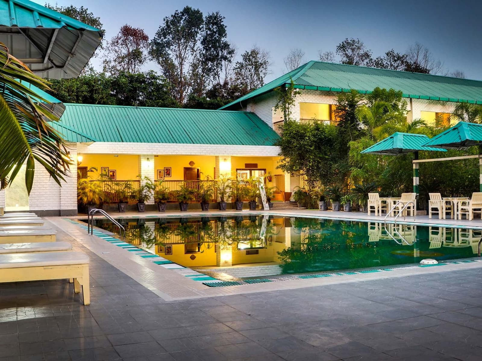 Serene outdoor swimming pool flanked by white sun loungers and green sloped roof buildings at Borgos Resort