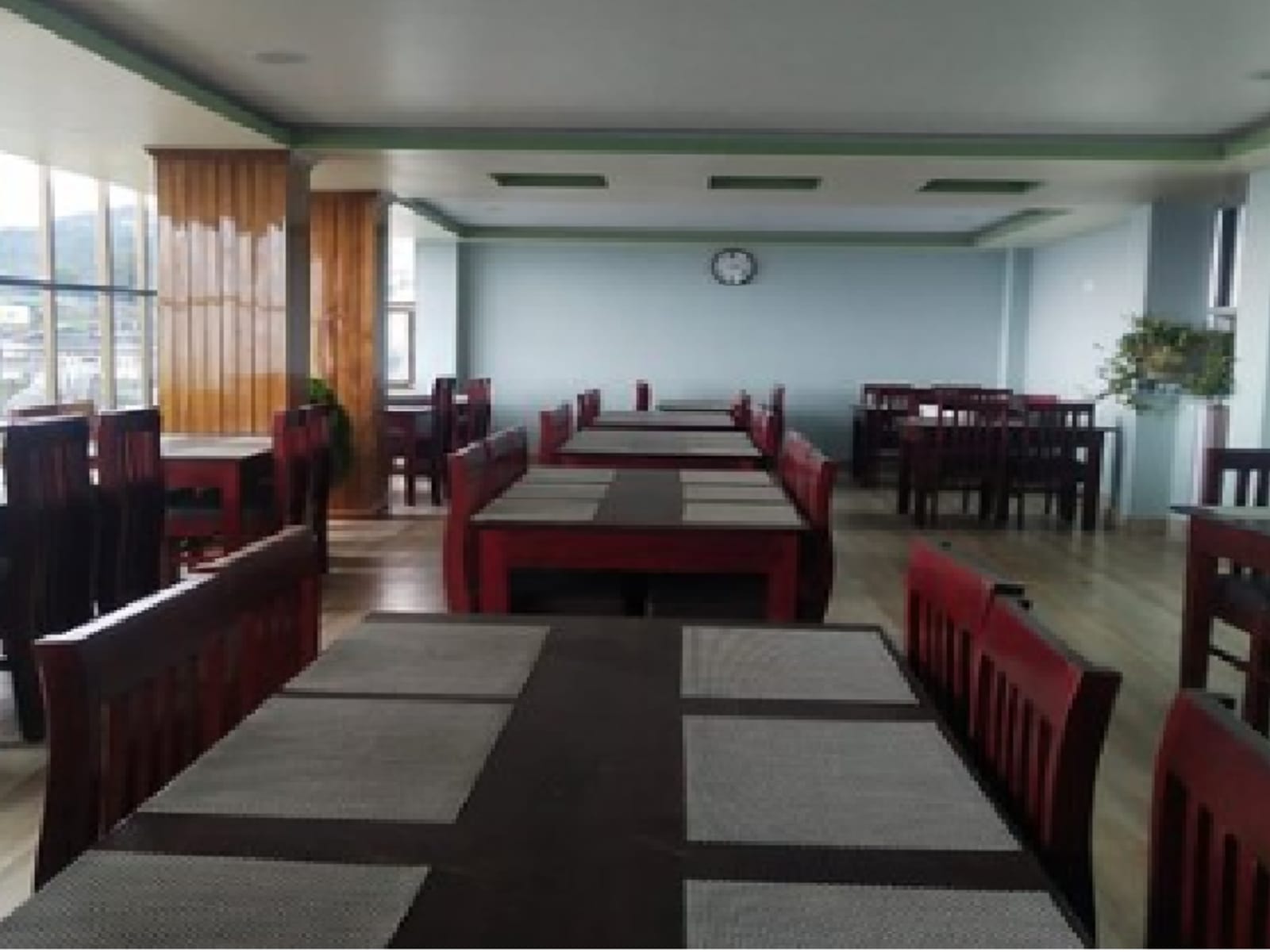 Restaurant dining hall perspective showing timber dining chairs and placemats.