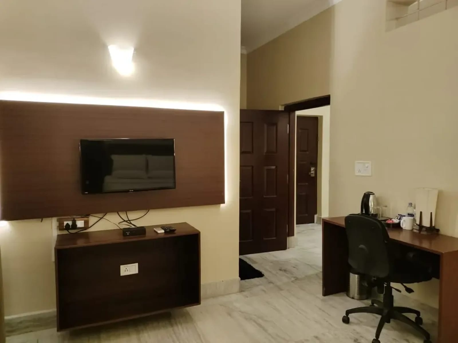 Flat-screen TV console with backlit panel, credenza, and dedicated work desk in Suite King Room.