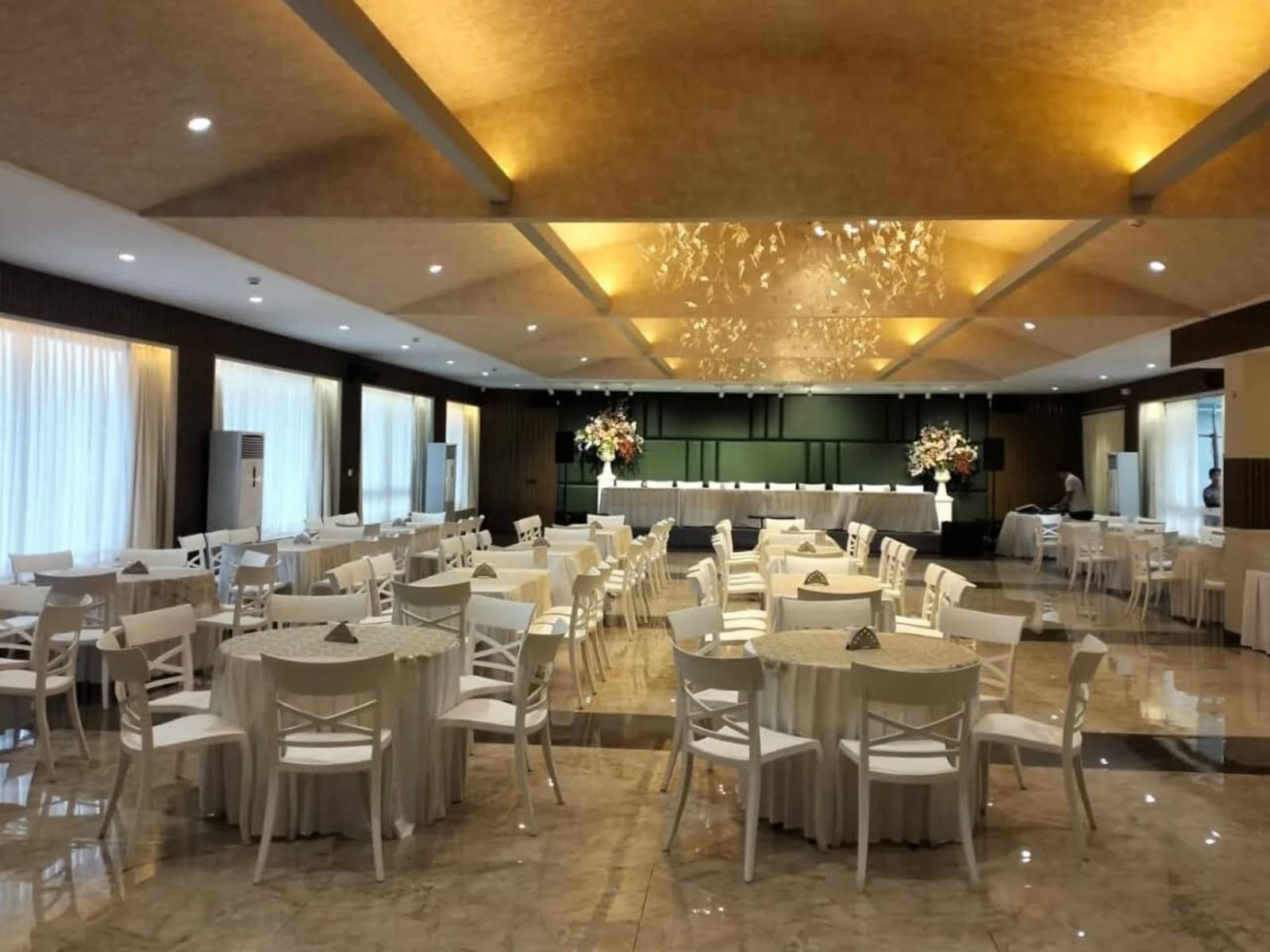 Banquet hall with round dining tables, white chairs, and ceiling butterfly chandeliers at Hotel Vivor.