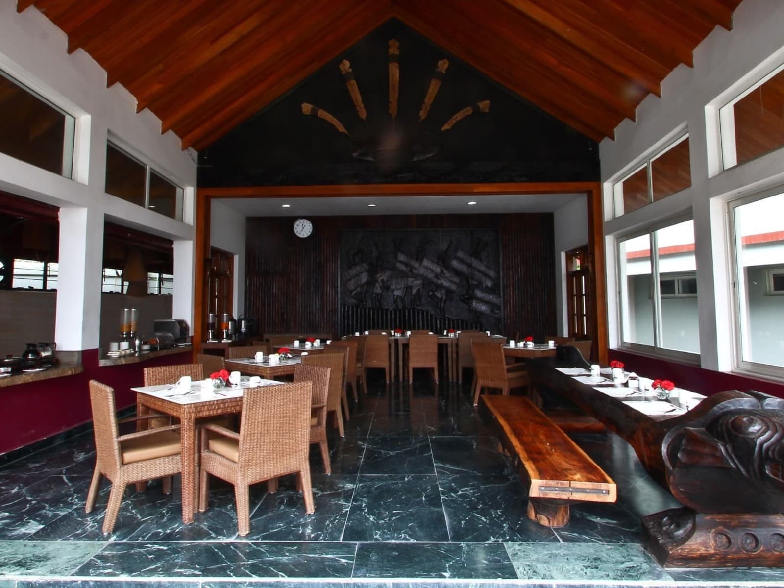 Morung Cafe dining room featuring vaulted timber ceiling, wicker chairs, and hand-carved Naga wooden bench.