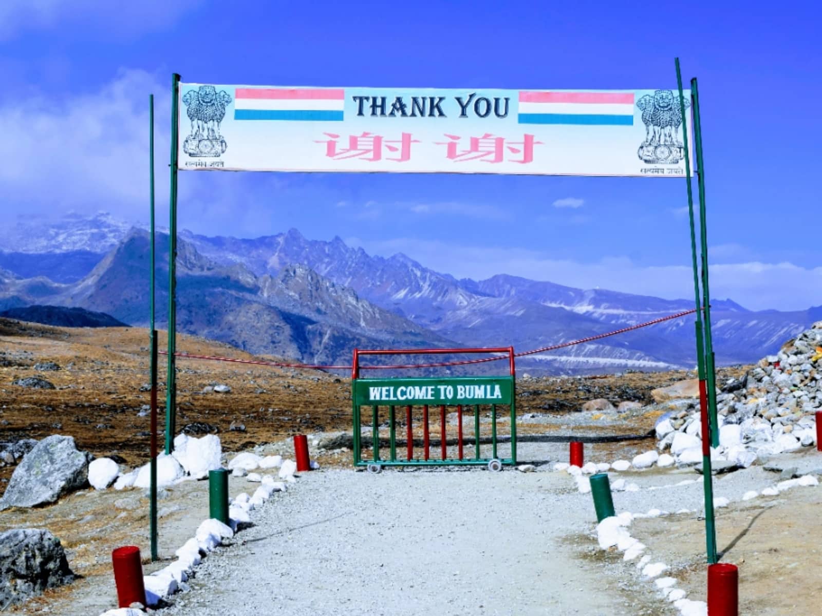 Border entry checkpoint with Welcome to Bum La barrier gate and bilingual Thank You banner.