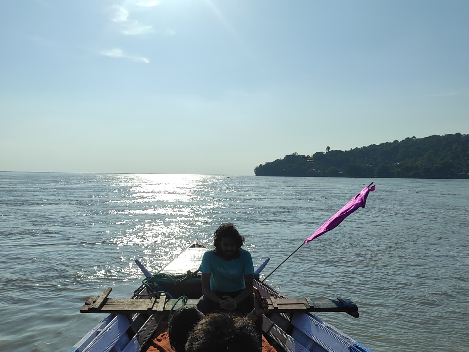 Tourists cruise along the broad Brahmaputra River in an engine-powered wooden boat on a freshwater dolphin excursion.