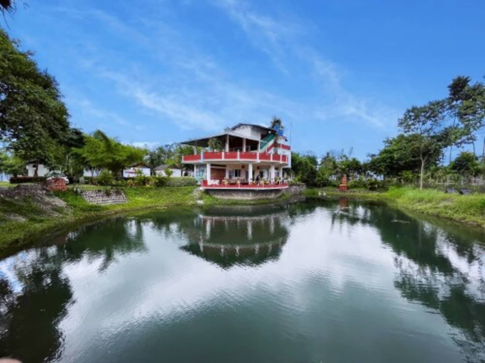 Covered dining pavilion and outdoor tables overlooking the garden pond at Manas Jungle Retreat