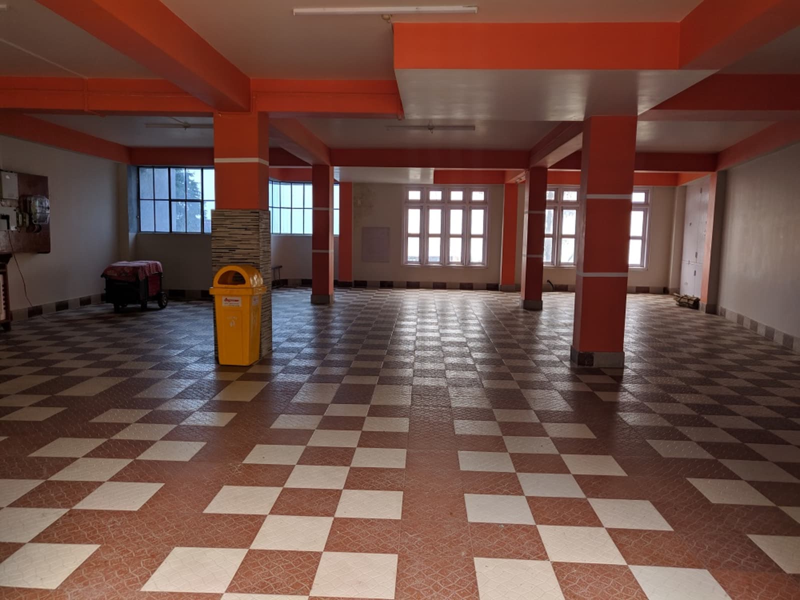 Covered vehicle parking bay on ground level featuring checkered tile flooring and painted pillars.