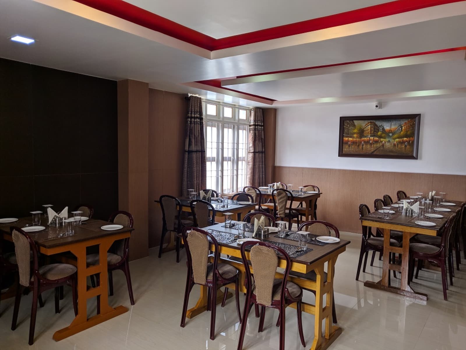 In-house dining hall with dark timber tables, cushioned chairs, and framed artwork along walls.