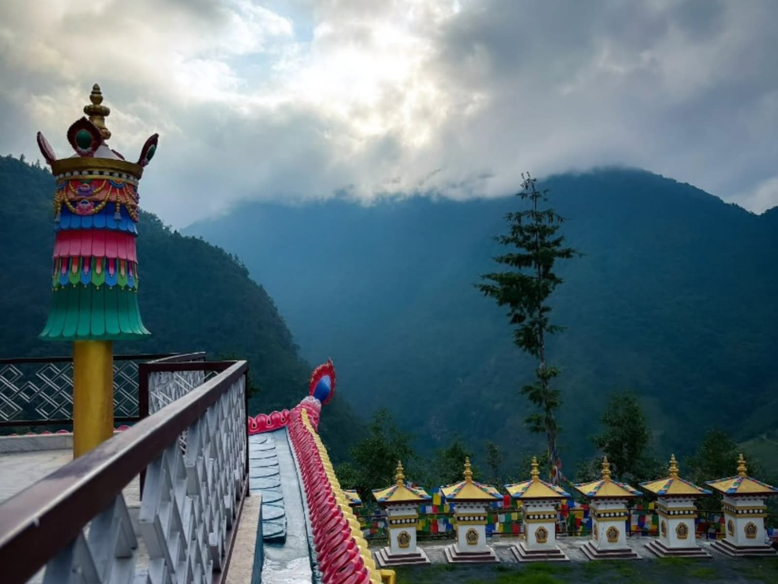 Terrace balcony with an ornamental finial overlooking miniature chortens and misty mountain ridges in Shergaon.