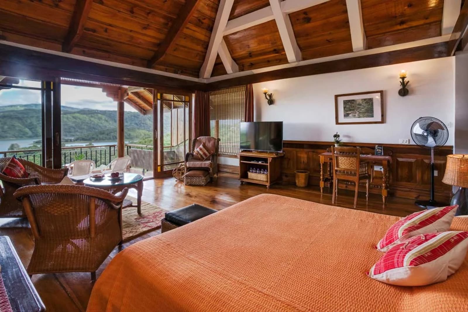 The Lake View Cottage bedroom offers an expansive king bed under vaulted red pine rafters opening toward the lake balcony.