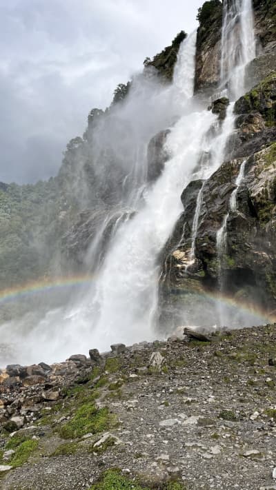 A natural mist rainbow appearing across the 100-meter cascade of Nuranang Falls.