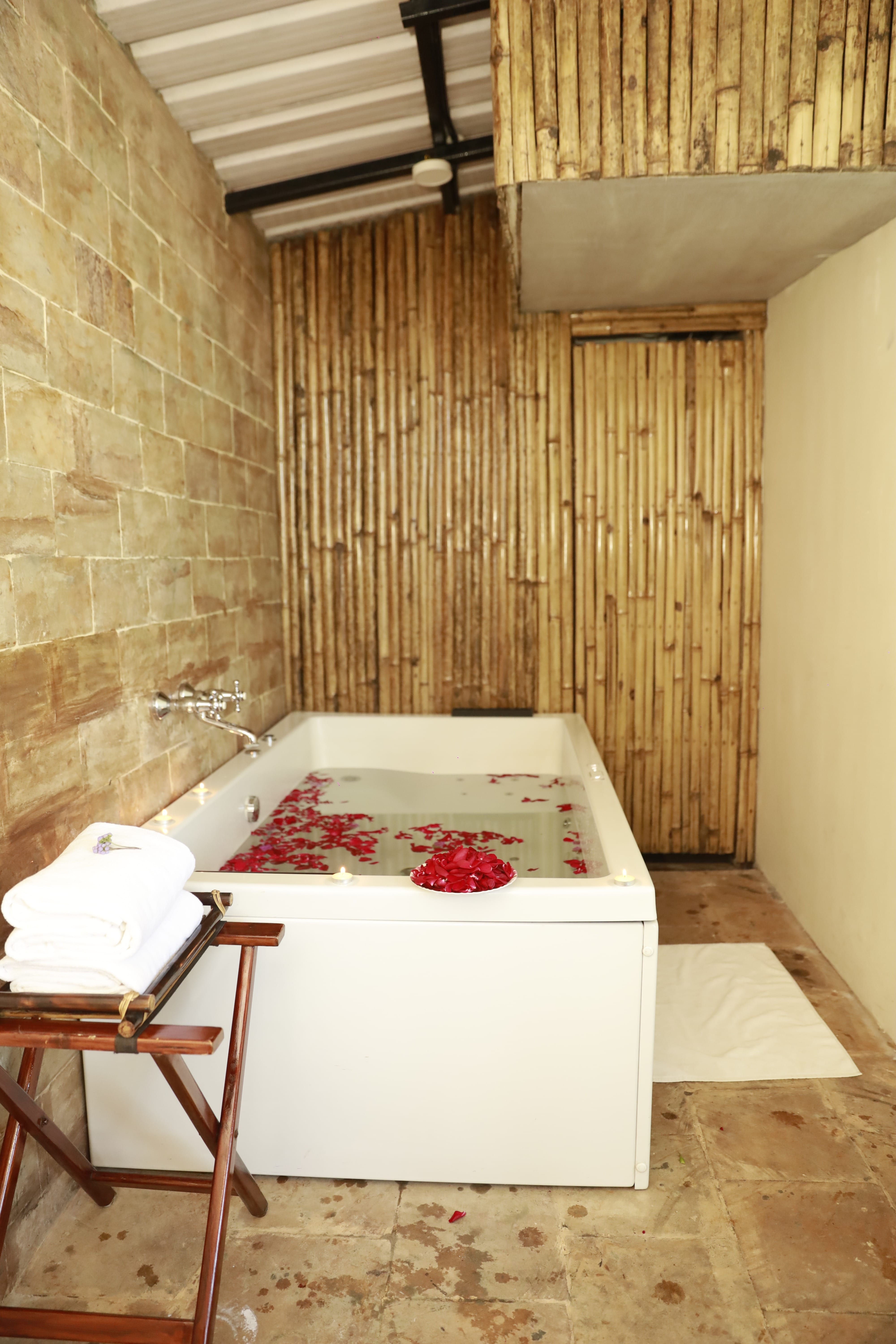 Rainforest Suite luxury bathroom featuring deep soaking tub adorned with fresh rose petals.