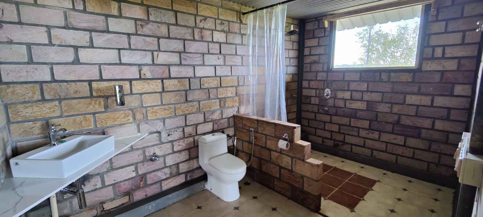 Attached modern stone masonry bathroom inside Valley View Cottage with rainfall shower.