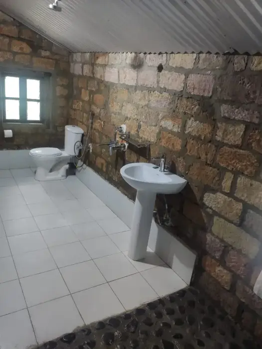 Attached bathroom facilities in Knup Mawiang featuring stone block walling and pedestal sink.