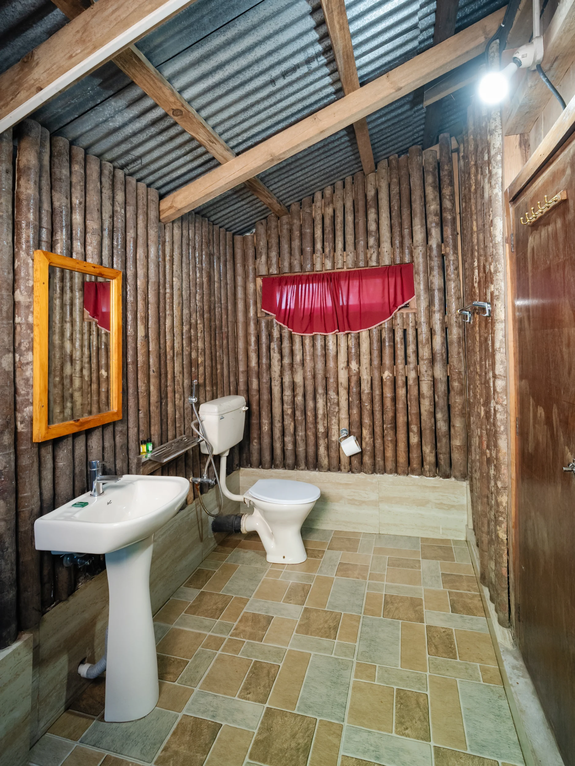 Attached rustic log-walled bathroom in Kynphor Cottage with wooden vanity mirror.