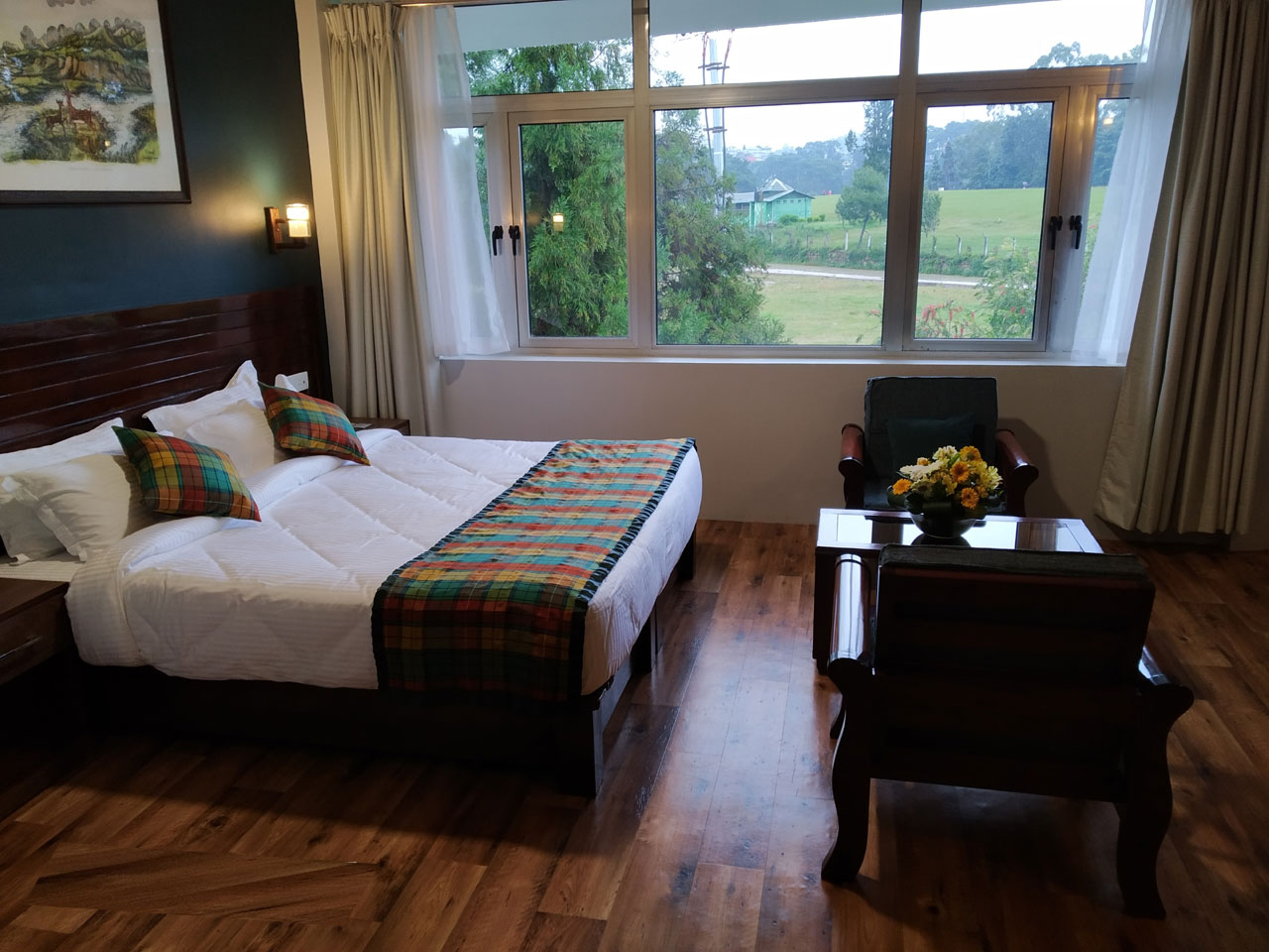 The Deluxe Room bedroom layout includes a king bed, hardwood flooring, and cozy seating beside golf green windows.