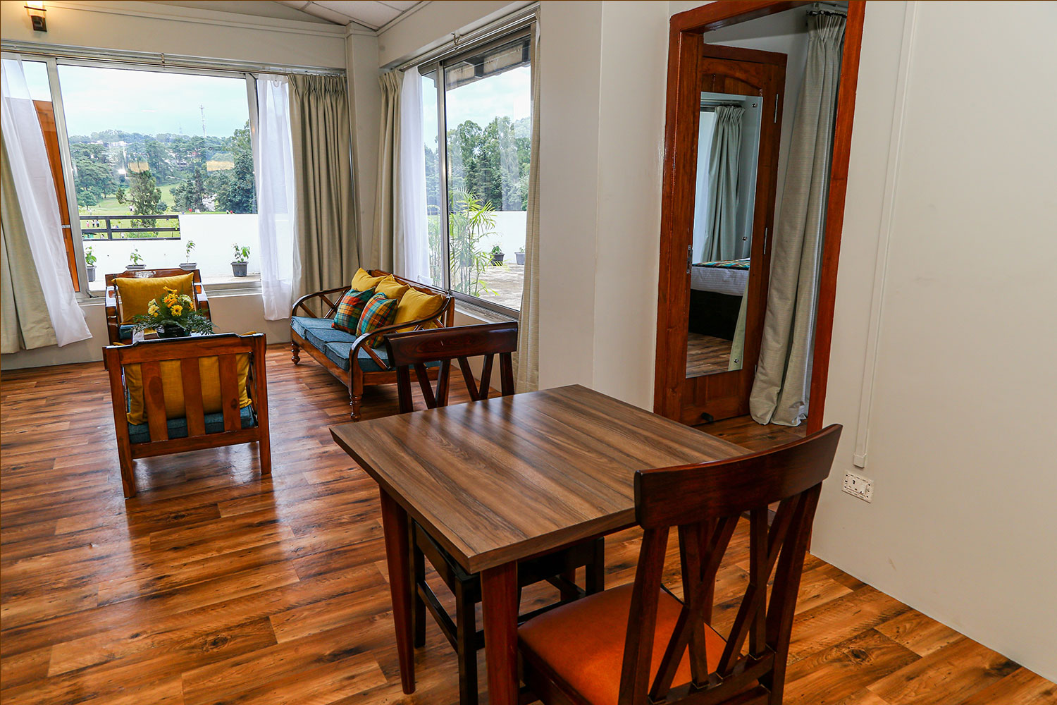 Suite Room separate living area equipped with a dining table set, sofa lounge seating, and floor-to-ceiling glass windows.