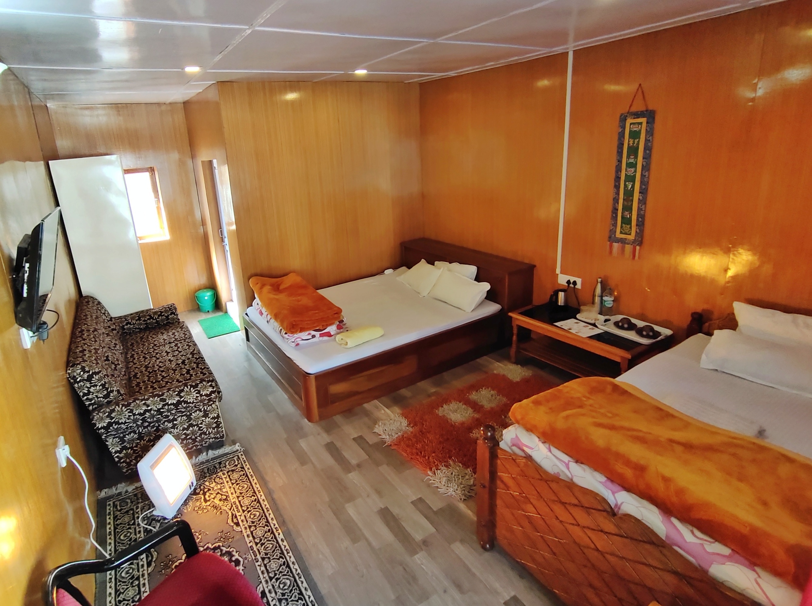 Soft overhead recessed lights illuminate the bedstead, floral couch, and floor heater.