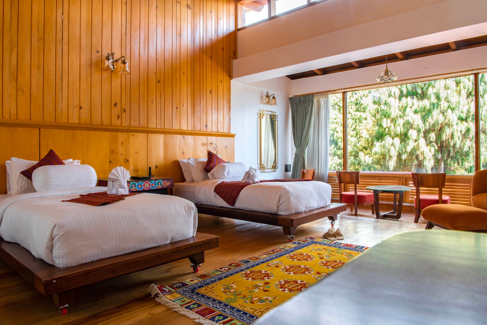Large glass panes reveal lush mountain foliage past the bedstead.