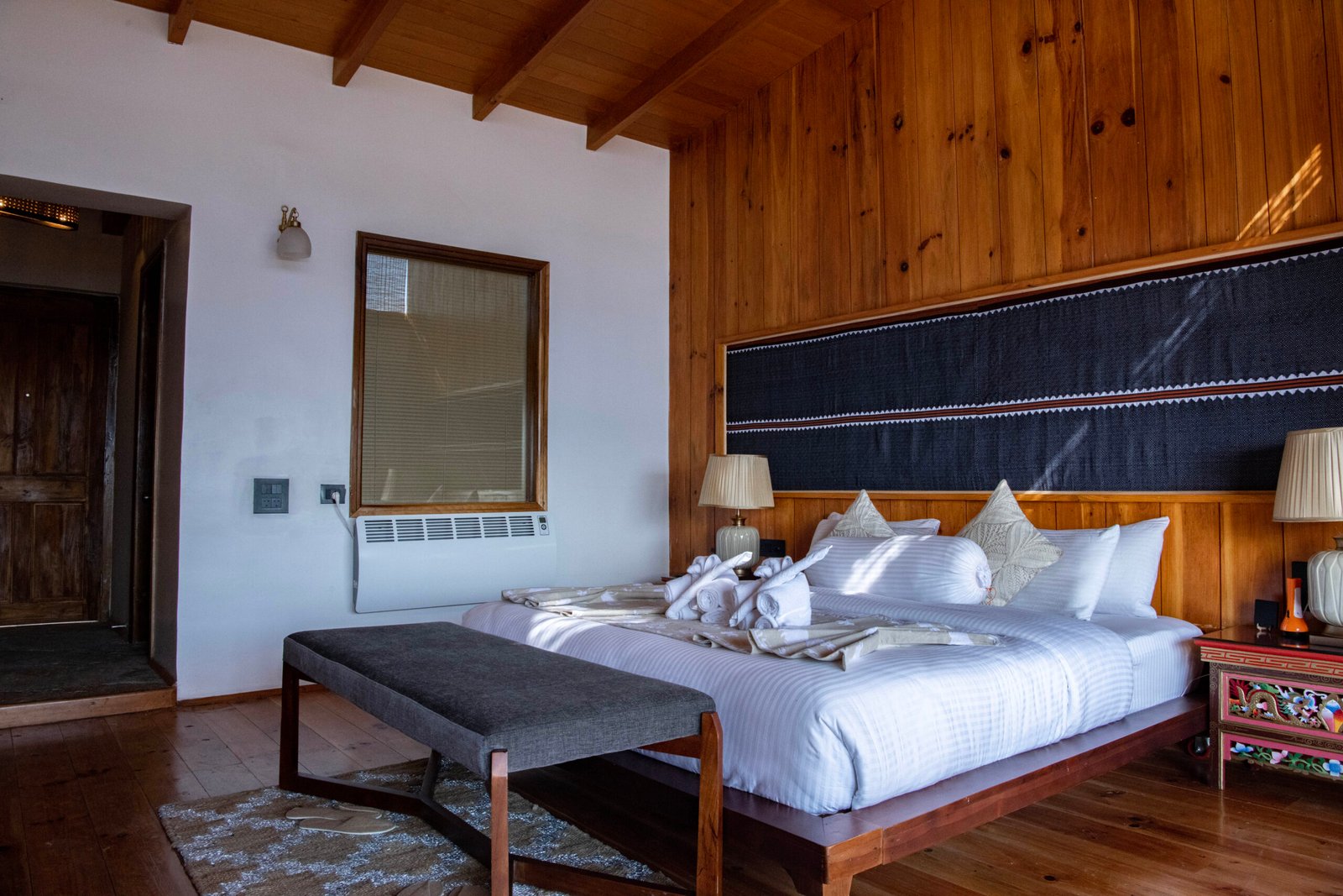 Heritage wooden wall finishes frame plush white bedding.