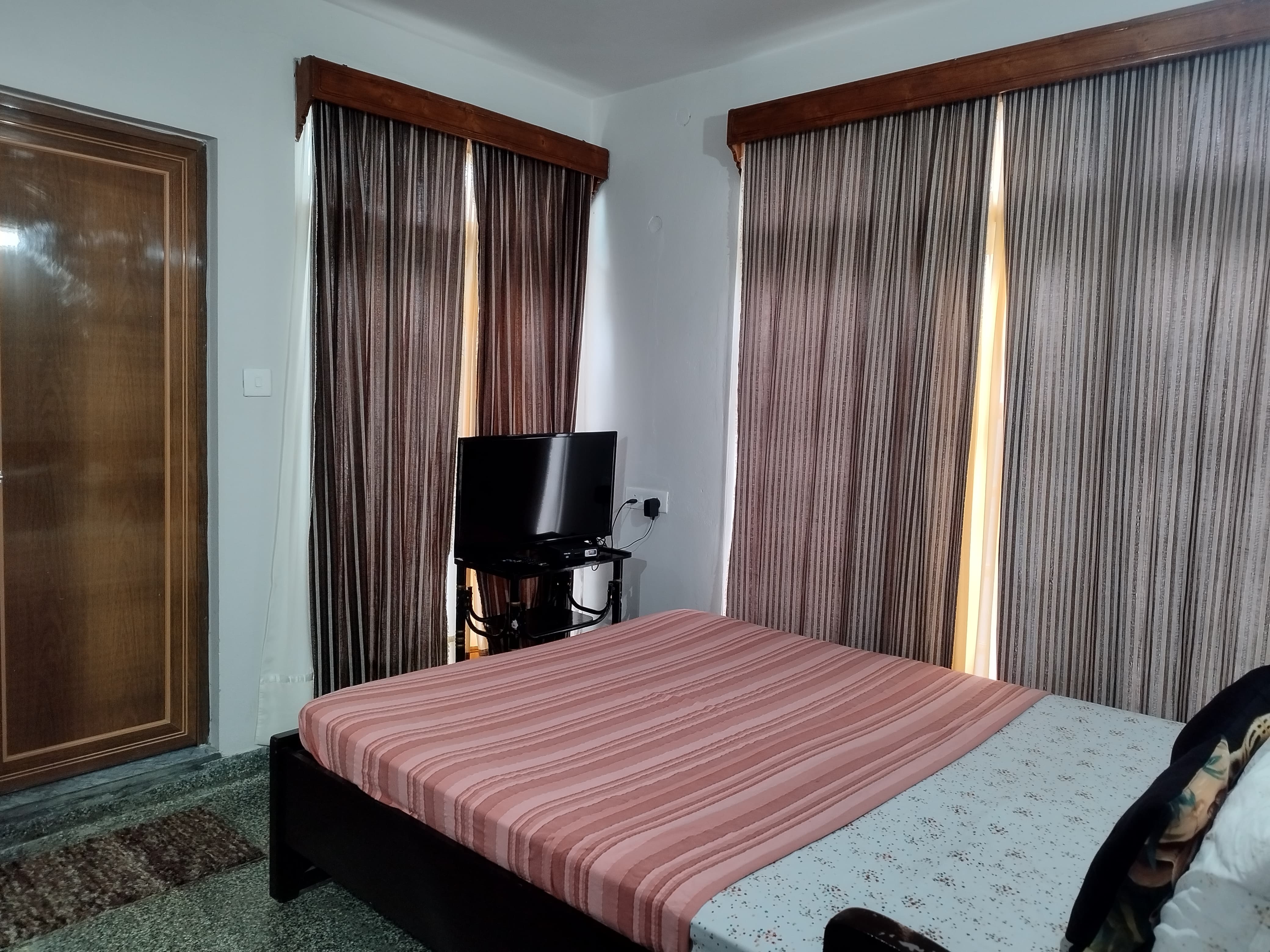 Double Room featuring a queen bed with striped bedding, blue bath towels, bedside lighting, and warm wood accents.