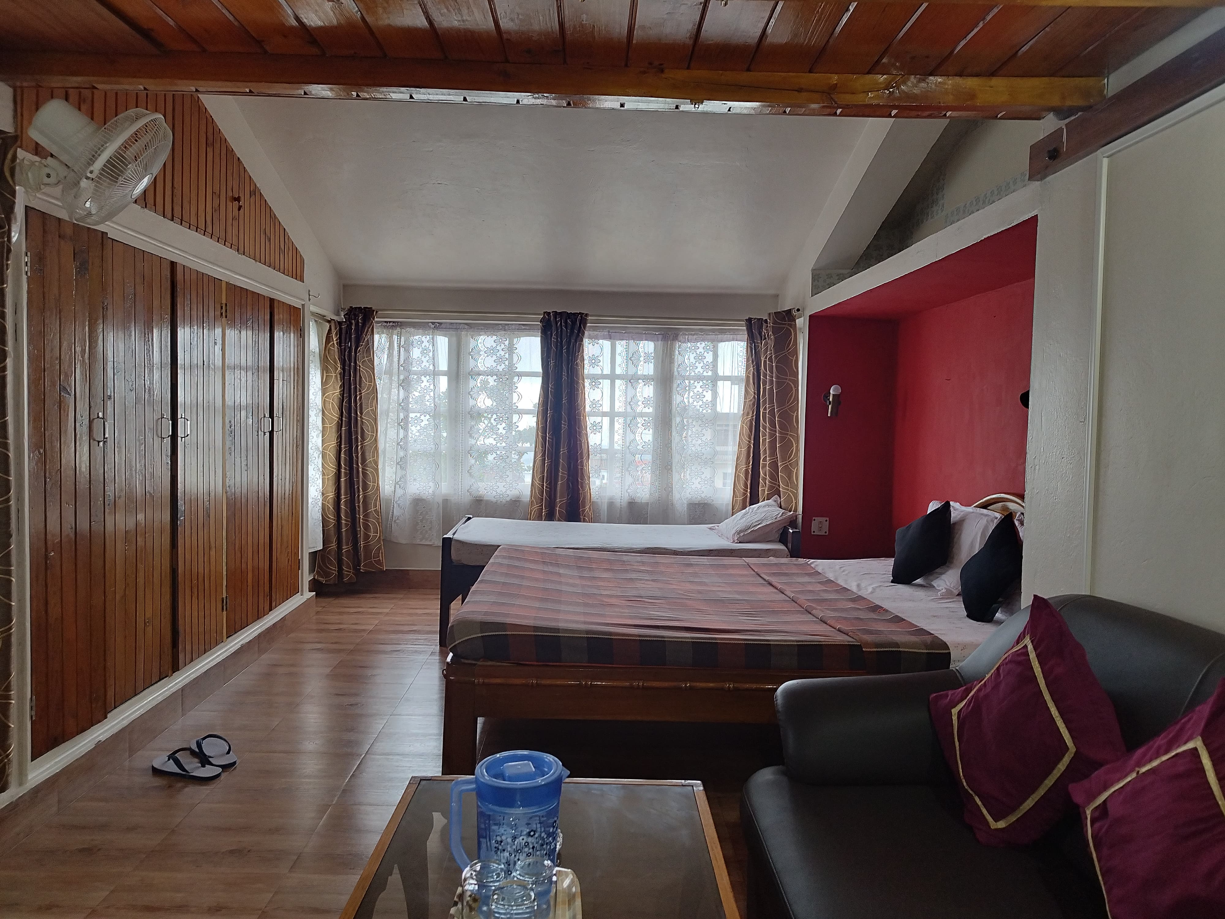 Spacious Suite Room featuring a queen bed tucked in a red accent alcove alongside an additional single bed.