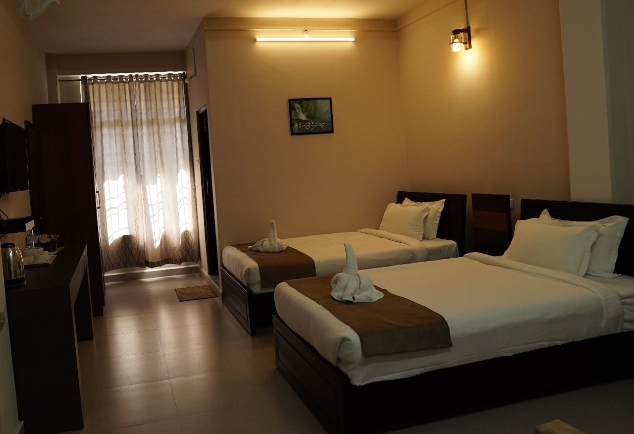 The Deluxe AC Room at Hotel Lavisto features comfortable twin single beds, an in-room electric kettle station, and warm ambient lighting.
