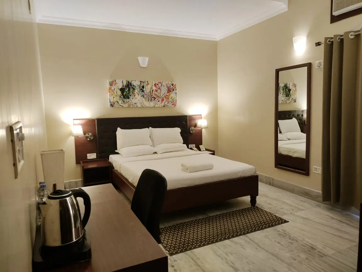 The master bedroom of the Suite King Room features a plush king-size bed, timber writing desk, in-room electric kettle station, and floor rug.