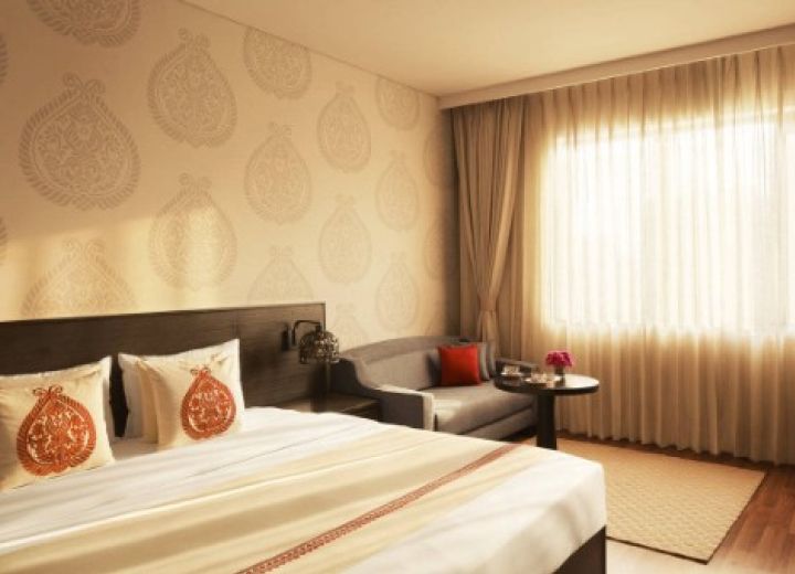 Superior Room master bedroom with king bed, embroidered cushions, and comfortable seating corner.