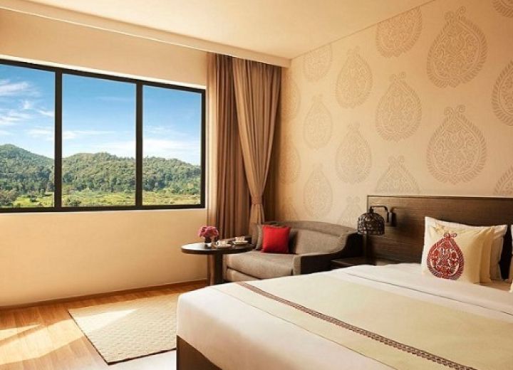 Deluxe Room bedroom with king bed and panoramic picture window facing the surrounding green hills.