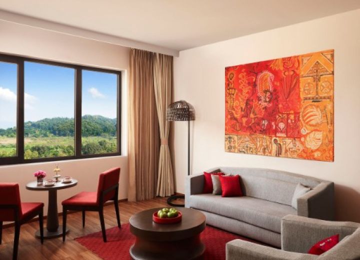 Spacious Premium Suite living room featuring vibrant Assamese artwork, plush sofa, and dining corner.