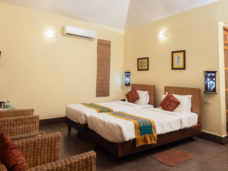 Striped Panthera cottage bedroom appointed with twin beds, woven cane headboards, air conditioning, and reading sconces.