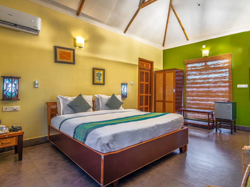 Grazing Rhino cottage bedroom with king platform bed, vaulted bamboo ceiling, wooden wardrobe, and in-room mini-fridge.