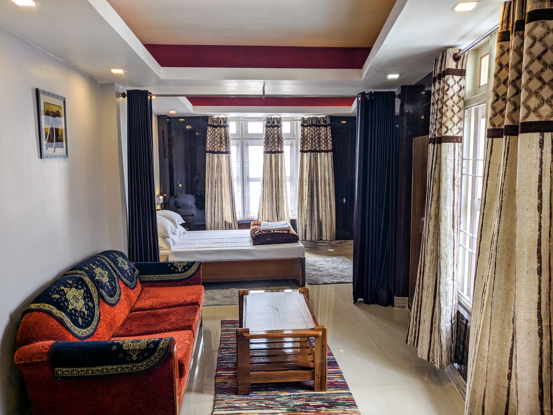 Spacious top-floor suite featuring king bedding, adjoining lounge corner, and full curtained windows.