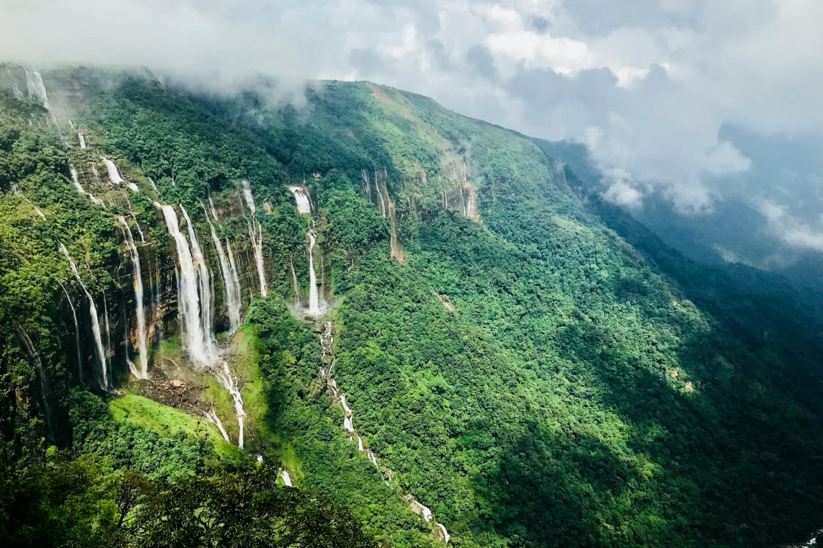 Seven Sisters Falls cascades down a lush green cliff in Cherrapunji, Meghalaya