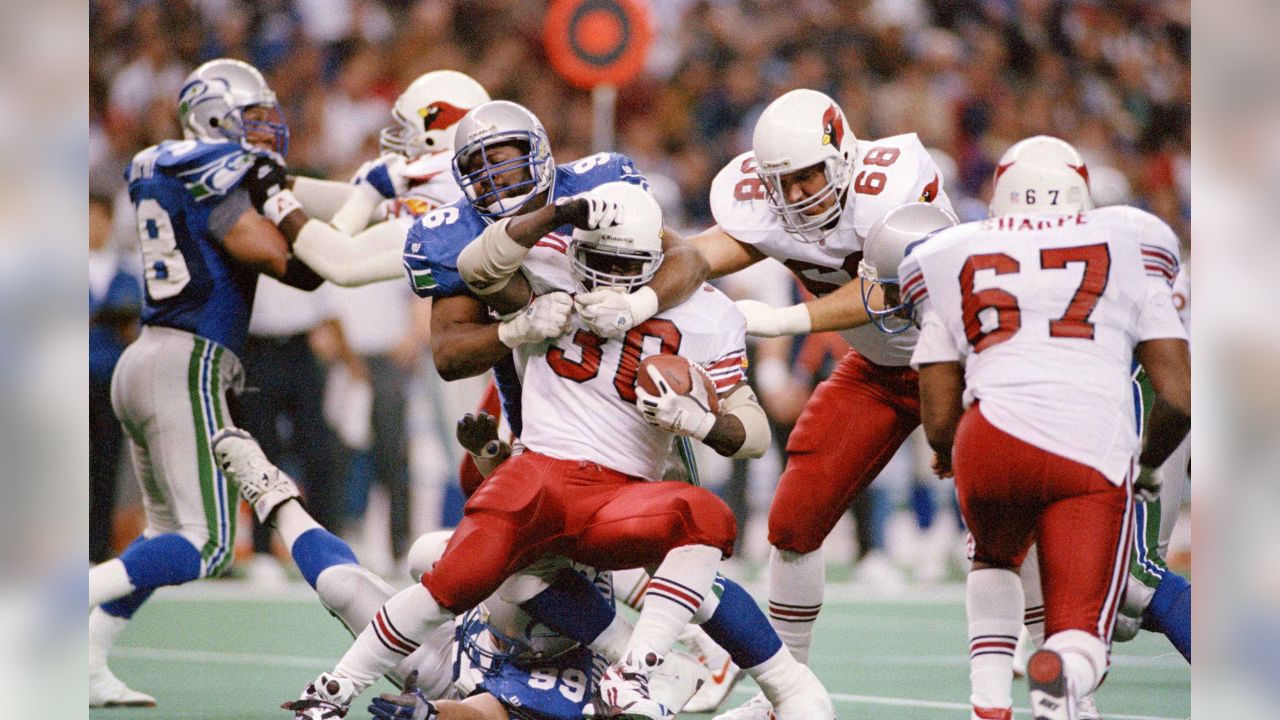 Running back Ron Moore (30) of the Phoenix Cardinals is held to a one yard gain as he is tackled by Cortez Kennedy (96) of the Seattle Seahawks during the third quarter of their NFL game in Seattle, Washington, Dec. 19, 1993. Watching the play is Joe Wolf (68) of the Cardinals. Phoenix beat Seattle in overtime, 30-27. (AP Photo/Bill Chan)