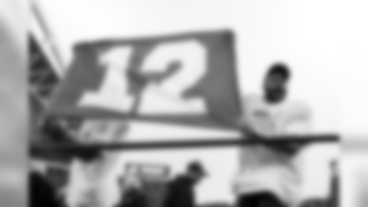 Seattle quarterback Russell Wilson celebrates with a 12 flag on the podium before the team was presented with the NFC Championship trophy.