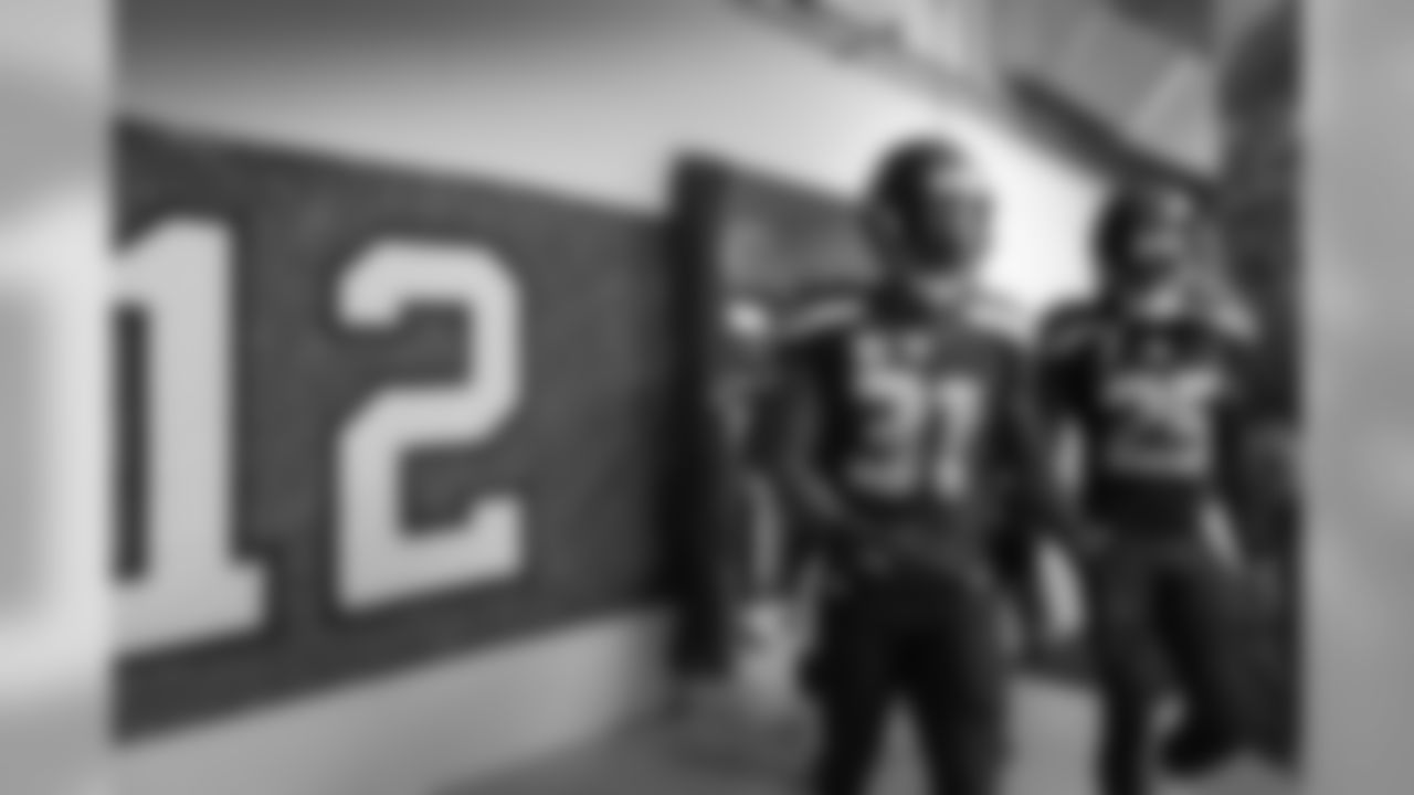 Legion of Boom members Kam Chancellor and Richard Sherman lead the defensive backs past a 12 flag signed by fans as they make their way out of the locker room for pregame warmups.