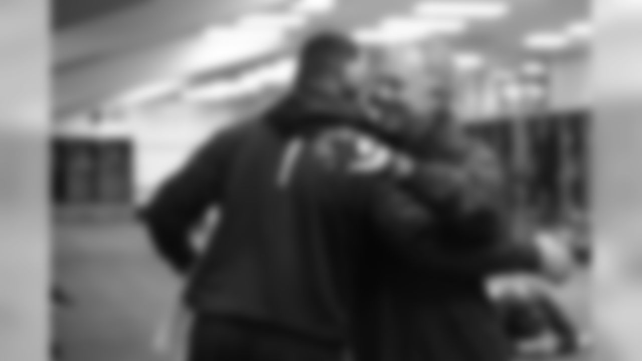 Quarterbacks coach Carl Smith gives a hug to Russell Wilson in the locker room.