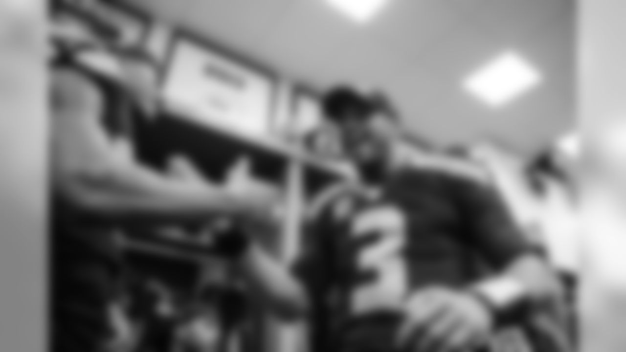 Quarterback Russell Wilson, wearing a NFC West Division Champions hat, celebrates with teammates after the team achieved one of their primary goal of the regular season.