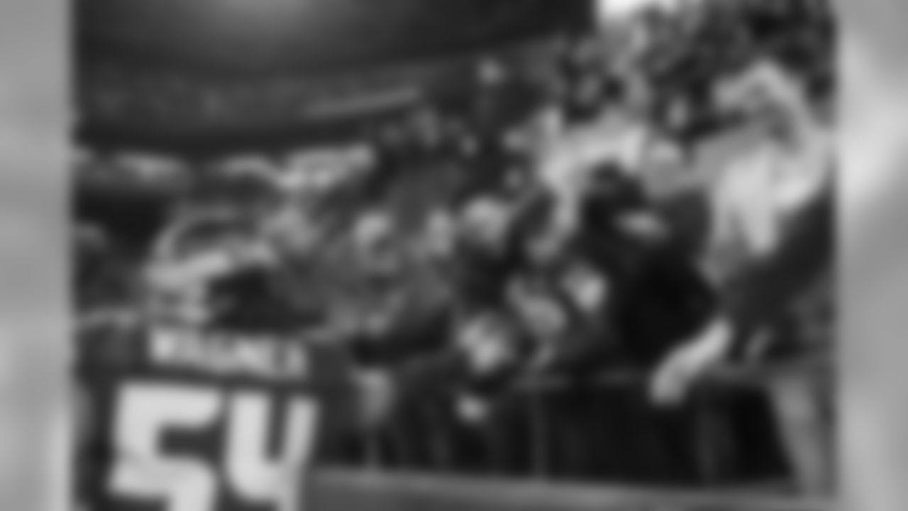 Seahawks linebacker Bobby Wagner hands the touchdown ball to a young fan seated near the end zone.